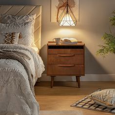 a bed room with a neatly made bed next to a night stand and a potted plant