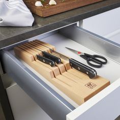 scissors and cutting board in drawer with knifes on counter next to utensils