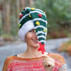 a woman wearing a knitted christmas hat and holding a candy cane in front of her face