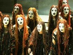 the group of women with long red hair are dressed in black and white masks,