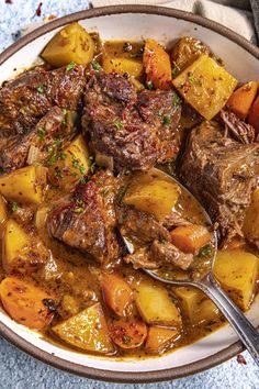 beef stew with carrots and potatoes in a skillet on a blue towel, ready to be eaten