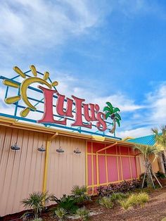 the exterior of a restaurant with palm trees and blue sky in the backround