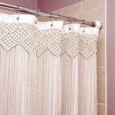 a shower curtain with white crochet on it in a bathroom next to a pink wall