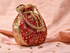 Red Potli Bag with Pearl Handle Strap An ideal for brides rocking the classic red bridal lehenga on their wedding with its classy zari work and a pearl handle strap all in gold the Dulhan Potli Bag is ready to beautify you. Fabric Raw Silk Color Red Embroidery Zari Work in Gold Size amp Dimensions Height - 8 inWidth - 7.5 inDepth - 1.5 in Strap Pearl Handle Strap Closure Tasseled Drawstring Compartments Single compartment Care Wipe with a soft clean amp dry cloth to remove dust When not in use s Bohemian Gold Bags With Latkans, Gold Bollywood Style Festive Bag, Bollywood Style Gold Festive Bag, Festive Bollywood Gold Bag, Gold Festive Pouch For Festivals, Festive Gold Pouch For Festivals, Red Handwork Potli Bag For Party, Gold Bohemian Potli Bag With Dori Work, Bohemian Gold Potli Bag With Dori Work