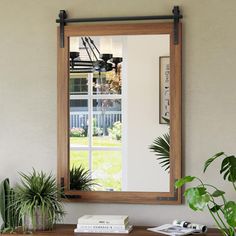 a mirror sitting on top of a wooden table next to a potted green plant