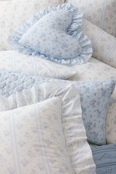 a bed with blue and white comforters, pillows and blankets on top of it