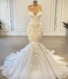 a white wedding dress on display in front of a mannequin headdress