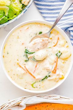 a white bowl filled with soup next to a salad