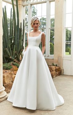 a woman in a white wedding dress standing next to a cacti and cactus