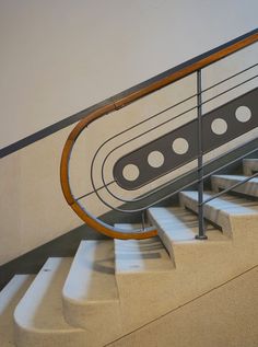 a metal hand rail on top of a set of stairs next to a white wall