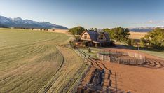 an aerial view of a farm with mountains in the background and a horse pen at the far end