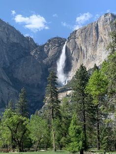 a large waterfall is coming out of the side of a mountain in front of some trees