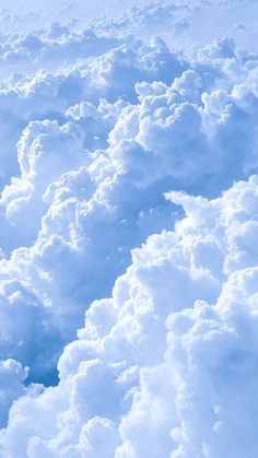 the view from an airplane window shows clouds and blue sky in the foreground, as seen from above