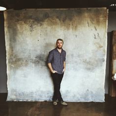 a man standing in front of a wall with his hands on his hips and looking at the camera