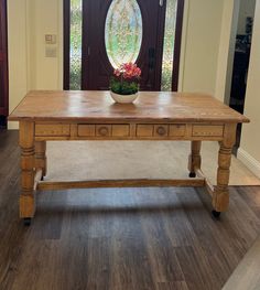 a wooden table sitting in front of a door with a potted plant on it