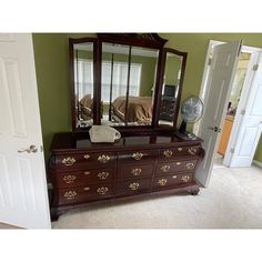 a dresser and mirror in a room with green walls