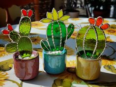 three small cactus plants sitting on top of a table covered in colorful glass beads and stones