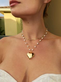 Make a statement with this elegant 18k gold heart pendant! Featuring a pearl chain for added sophistication. Made with 18k plated gold over stainless steel. Length: 16.5 in with a 2 in extender chain Pendant Width: 30mm Puffy Heart Necklace Outfit, Statement Necklace Aesthetic, Elegant White Chain Necklace For Valentine's Day, Gold Necklace With Pearl Chain For Valentine's Day, Valentine's Day Gold Necklace With Pearl Chain, Valentine's Day Gold Pearl Chain Necklace, Gold Pendant Pearl Necklace With Heart Charm, Gold Heart Necklace With Pearl Charm As Gift, Gold Pearl Necklace With Heart Charm And Pendant