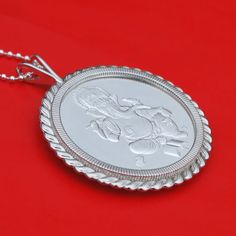 "A gorgeous sterling silver necklace, set with an authentic 1 oz Silver Round - Ganesha. Obverse: Traditional image of Ganesha attended by a mouse, which is commonly seen. Reverse: Hindi text for \"Hinduism,\" along with the weight, purity and year of issue. The coin bezel frame is well designed with classic ropes, about 2.32\"(59mm) x 1.84\"(47mm), and made of solid 925 sterling silver. It comes with a 24\" 925 sterling silver chain and also a beautiful gift box, so the pendant is ready to wear Engraved Temple Jewelry As A Gift, Silver Round Pendant Necklace For Diwali, Classic Jewelry For Festivals And Gifts, Sterling Silver Jewelry For Festivals As A Gift, Sterling Silver Jewelry For Festivals And Gifts, Sterling Silver Necklaces For Festivals And Gifts, Silver Amulet Necklace For Diwali, Festival Coin Pendant Jewelry As Gift, Temple Jewelry Gift With Oval Shape