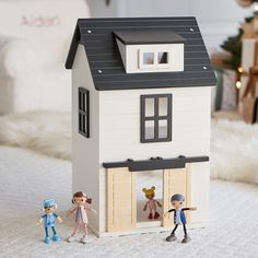 two small figurines are standing in front of a doll house with the door open