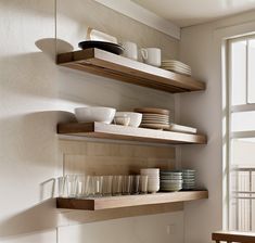 some shelves with plates and bowls on them in a dining room or kitchen area that is well lit by the window