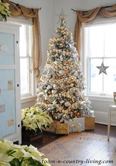 a decorated christmas tree in the corner of a living room with white and gold decorations