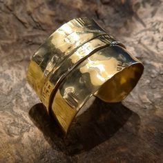 This unique and cool fold-formed brass wide cuff bracelet will always be the center of attention. Many of our designs are inspired by our fascination with the ancient cultures of the world, and this particular bracelet was inspired by the culture and lifestyle of the Vikings! This brutalist unisex cuff bracelet is made of brass. It is hammered, fold-formed, textured and polished entirely by hand in our studio. This handmade cuff bracelet is perfect for both women and courageous men... Its width is 4 cm. This cuff is adjustable, it can easily be squeezed for a tight fit or pried open for a looser fit. But even so, for its length, please select your size (considering the size of your wrist circumference) via the drop-down menu so that we can precisely prepare it for you.  Every piece in our Luxury Bronze Brass Bracelets, Luxury Bronze Cuff Bracelet As Gift, Unique Gold Wide Band Cuff Bracelet, Gold Brass Wide Band Cuff Bracelet, Gold Brass Cuff Bracelet With Wide Band, Gold Wide Band Cuff Bracelet In Brass, Unique Gold Wide Band Bracelet, Handmade Gold Cuff Bracelet With Wide Band, Handmade Wide Band Gold Cuff Bracelet