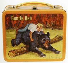 a child is on top of a bear in a tin lunch box that says gentle ben