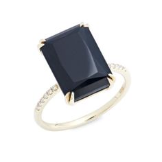 a gold ring with a black stone and diamonds on the sides, in front of a white background