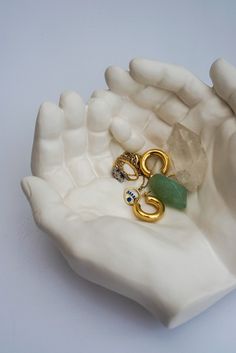 a hand holding a ring with two gold rings and a green bead on it