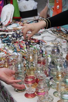 a table topped with lots of glass jars filled with different types of beads and necklaces