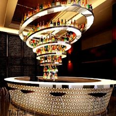 a bar with lots of liquor bottles on the top and below it is a circular chandelier that hangs from the ceiling