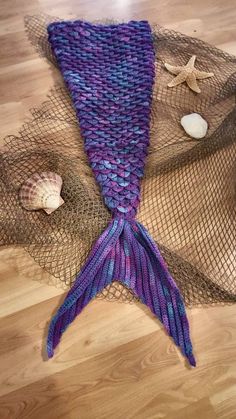 a purple and blue mermaid tail laying on top of a wooden floor