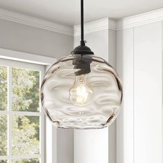 a glass light fixture hanging from a ceiling in a room with white walls and windows