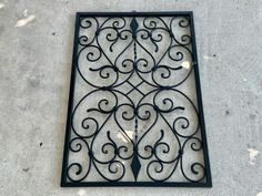 a decorative iron grate sitting on the ground in front of a wall or floor