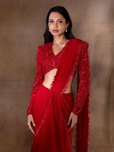 Red flowy skirt with an attached hip cowl drape, pleats & an attached pallu hand embellished with red pearl drops & glass bugles, paired with a power shoulder structured V neck full sleeve blouse featuring red floral hand embroidery.From Shloka Khialani's Winter Sun collection.DELIVERY TIMEPlease allow 6-8 weeks for your outfit to arrive.FABRIC DETAILSGeorgette, Net, CrepeProfessional cleaning only. Red Drape Saree, Pre-draped Blouse With Draped Sleeves For Party, Party Blouse With Pre-draped Sleeves, Evening Saree Dress With Draped Sleeves, Festive Gown With Draped Sleeves, Festive Gown With Traditional Draped Sleeves, Full Sleeve V Neck Blouse Designs, Festive Dresses With Pre-draped Sleeves, Festive Dresses With Pre-draped And Draped Sleeves