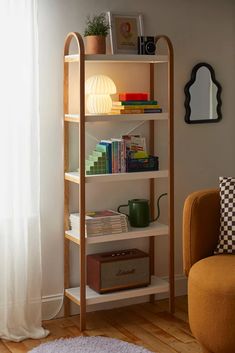 a living room with a chair, bookshelf and lamp on the floor next to a window