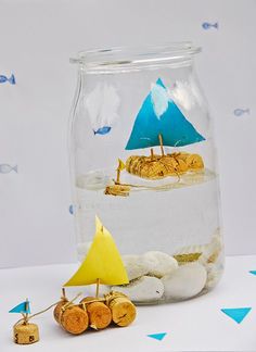 a glass jar filled with sand and small toy sailboat in it's bottom