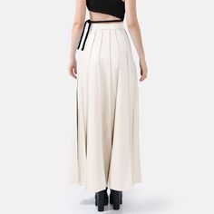 Step into effortless elegance with the Solace Vegan Leather Pleated Maxi Skirt in white. With a hidden zip closure and stylish golden embellishments, this skirt combines sophistication with a touch of luxury. The lightweight fabric drapes beautifully, offering a relaxed yet structured fit with just the right amount of stretch for comfort and durability. The vertical hand-pleating creates a flattering silhouette by elongating the lower body. Perfect for stylish occasions where comfort is key, thi Elegant High Waist Beige Culottes, Luxury Pleated Skirt For Spring, Elegant Beige Wide Leg Culottes, Elegant White Wide Leg Maxi Skirt, Luxury White Bottoms For Evening Wear, Luxury White Bottoms For Evening, Chic Beige Pleated Skirt For Party, Elegant Beige Asymmetrical Skirt, Luxury White Skirt For Spring