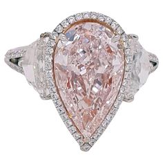 Absolutely stunning engagement ring style showcasing a Fancy Light Pink 3.25 carat pear-shaped diamond certified by GIA as VS2 clarity. The center stone surrounded by a round brilliant white diamonds halo, Flanked by two Cadillac cut diamonds total weight 1.29 ct. SI1 clarity, E color. Set in a polished 18K white gold. Total diamonds weight: 5.27 carat. This piece was handmade at the Novel Collection Jewelry Atelier, which specializes in rare collectible pieces in the Fancy color diamond. For many jewelry lovers, a fancy pink diamond represents the Platonic ideal. They combine the diamond's significant hardness and brilliance with a spectacular uniqueness found nowhere else on earth, embodying three key attributes: hardness (ranking 10 on the Mohs scale), rarity, and beauty. When the Argyl Pink Cushion Cut Engagement Ring, Pink Diamond Ring Engagement, Jewelry Atelier, Pink Diamonds Engagement, Engagement Ring Style, Pink Diamond Engagement Ring, Fancy Light, Pink Emerald, Pink Diamond Ring