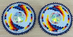 pair of colorful beaded earrings with crystal center on wooden table top, closeup