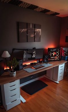 a desk with a computer and speakers on top of it in a room that has wood floors