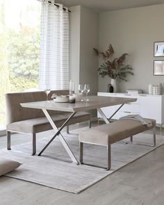 a dining room table with two benches in front of it and a vase on the side