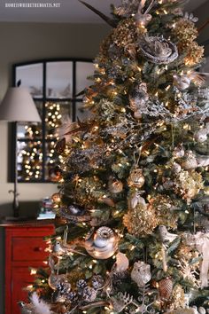 a christmas tree is decorated with silver and gold ornaments, pineconi balls, and other holiday decorations