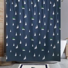 a blue shower curtain with white trees and trucks printed on it in a bathroom next to a toilet