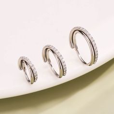 three silver rings with small diamonds on top of a white plate next to each other