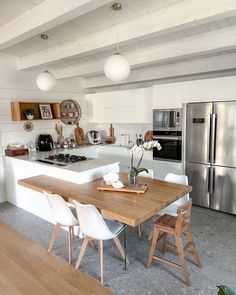 a kitchen with white walls and wooden table in front of stainless steel refrigerator freezer