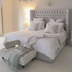 a bed with white sheets and pillows in a room