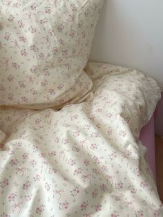 an unmade bed with white sheets and pink flowers on it's comforter