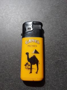 a yellow lighter with a camel on it's side and the words gamol filters written in arabic